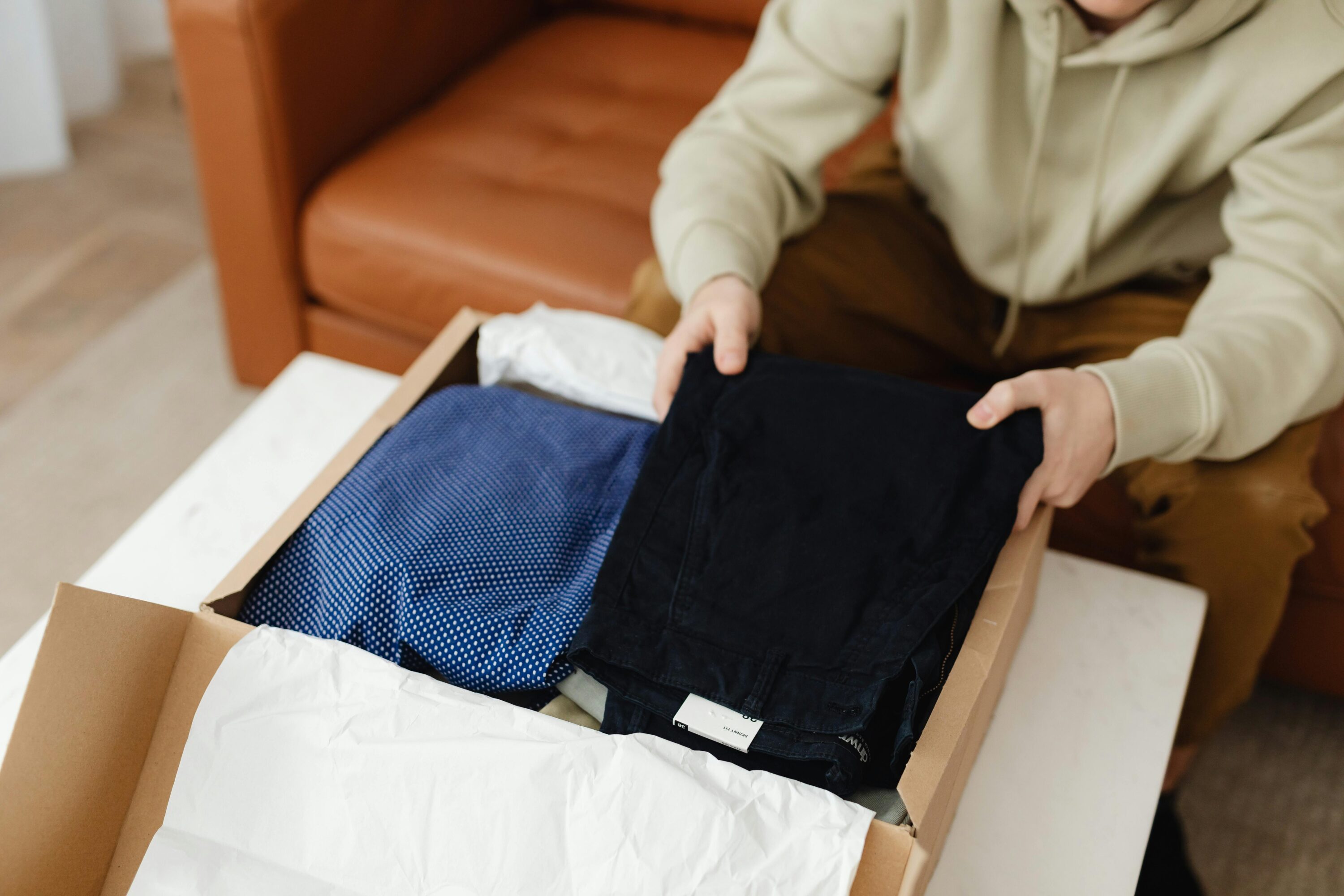 Hands seen unpacking a clothing delivery from an eCommerce website.